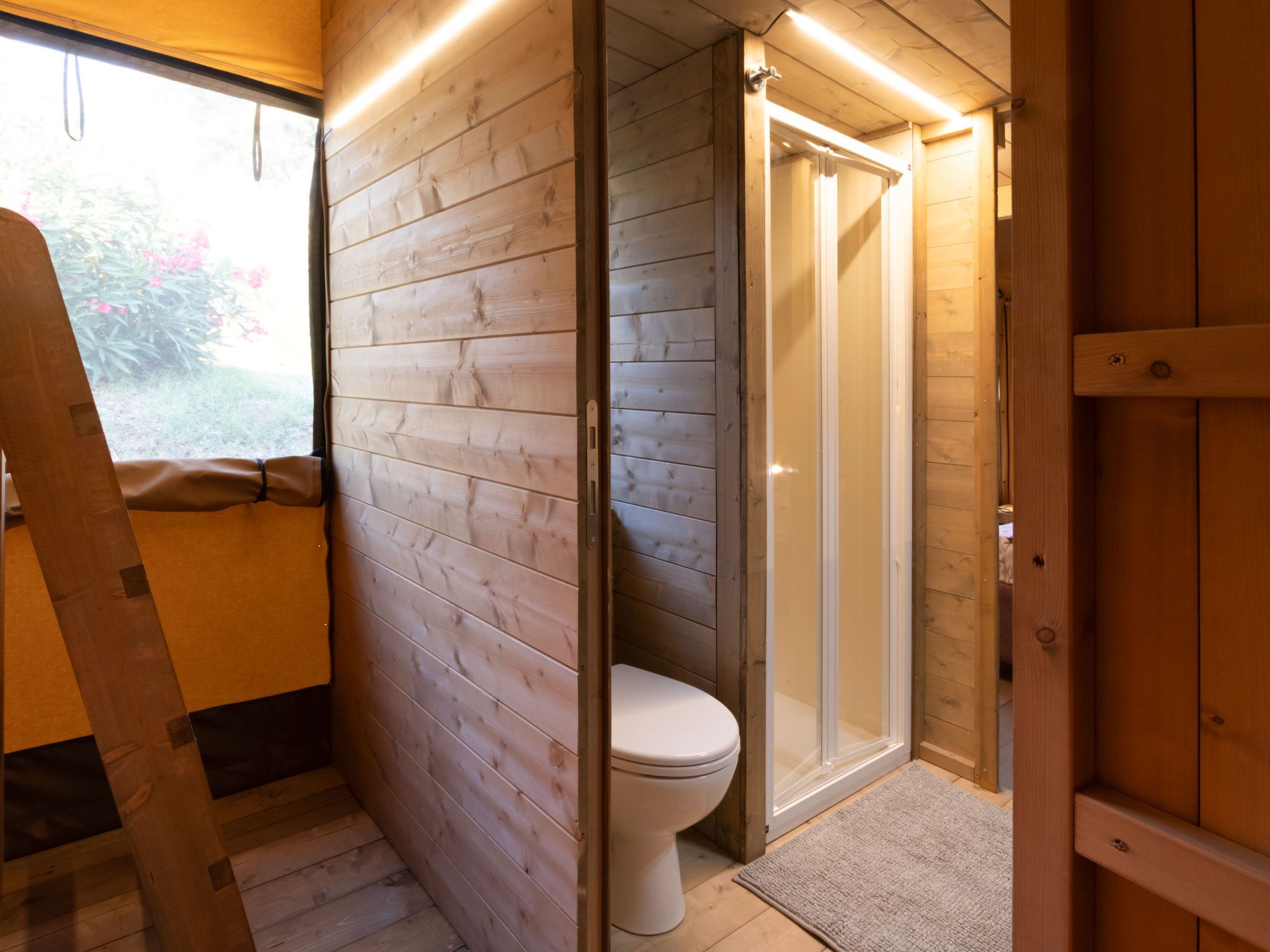A wooden interior with a toilet and a shower.