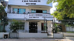 A two-story building named "Casa Negrete Hostel Boutique" with a balcony, a gate, and a contact number.