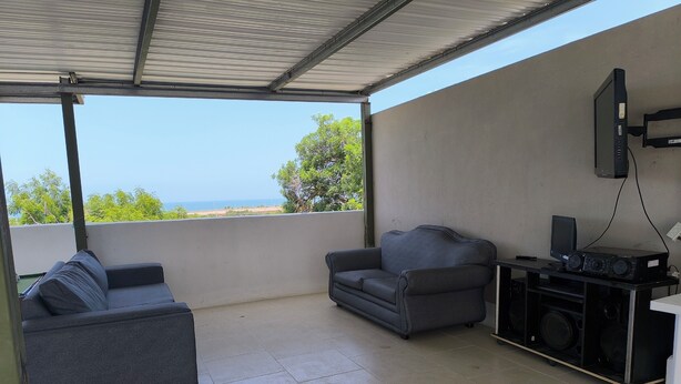 A covered outdoor seating area with two sofas and a sound system.