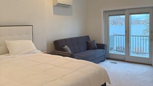 A bedroom with a bed, a sofa, and a sliding glass door leading to a balcony. - Charming 3-bedroom house in peaceful White Lake Township on Pontiac Lake (White Lake Township)