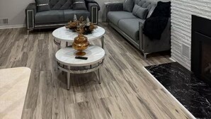 A modern living room with two grey sofas, a white fireplace, and a round coffee table with decorative items. - Charming 3-bedroom house in peaceful White Lake Township on Pontiac Lake (White Lake Township)