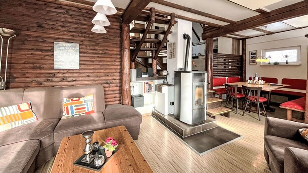 A modern living room with a wooden wall, a sofa, a coffee table, and a fireplace.
