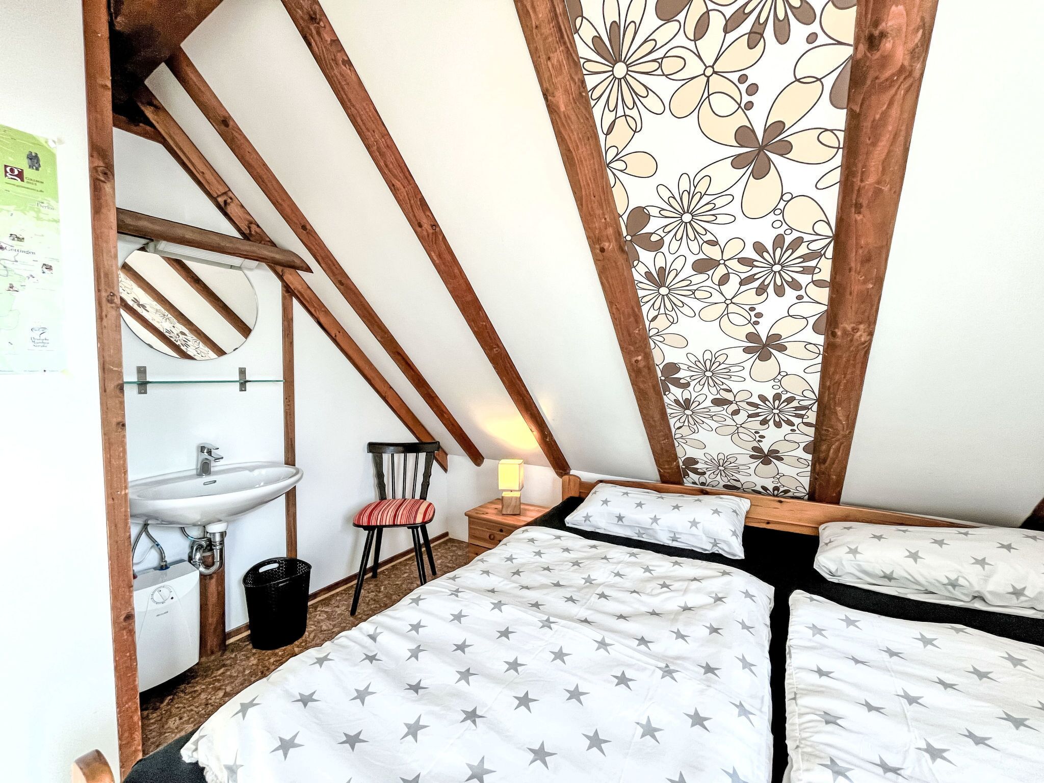 A bedroom with a bed, a chair, a sink, and a mirror.