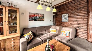 A cozy living room with a brown leather sofa, a wooden coffee table, and a cabinet with glassware.