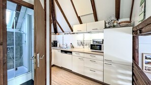 A modern kitchen with wooden beams, white cabinets, and a built-in microwave.