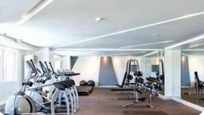Ein Fitnessstudio mit Ergometer, Krafttrainingsgeräten und Kurzhanteln.