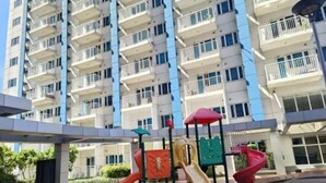 Ein Spielplatz mit Rutschen und Klettergerüsten vor einem Wohngebäude.