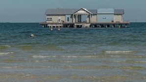 Un edificio frente al agua con un muelle que se adentra en el agua.