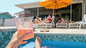 Un área junto a la piscina con sillones de descanso y una sombrilla.