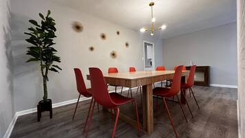 A conference room with a wooden table, red chairs, a potted plant, and decorative wall sconces.