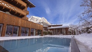 Un bâtiment en bois avec une piscine et des environs enneigés.