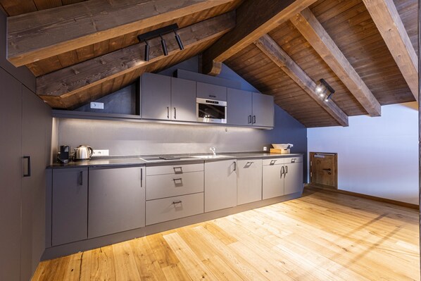 A modern kitchen with grey cabinets, a stainless steel oven, and a wooden ceiling. - Welcoming Chalet With Balcony (Ehrwald)
