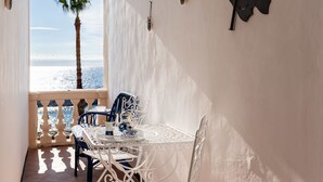 Ein sonnendurchflutetes Zimmer mit Tisch und Stühlen, Blick auf das Meer durch einen Bogen sowie dekorative Wandelemente.