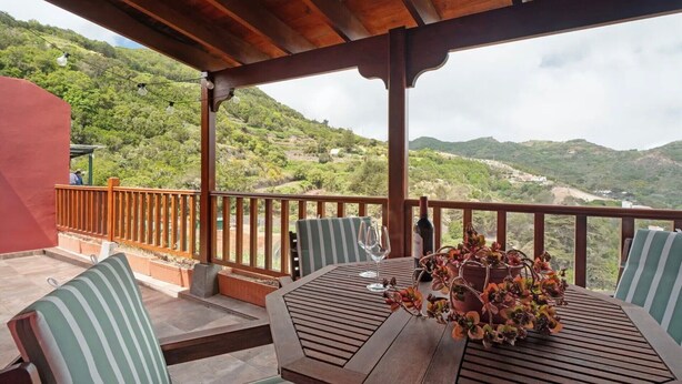 A covered outdoor seating area with a table, chairs, and a view of a mountainous landscape. - 'Tilo' Apartment with Mountain Views, Wi-Fi and Air Conditioning - SilboHolidays (Santa Cruz de Tenerife.)