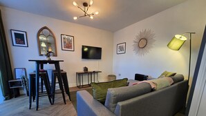 A modern living room with a grey sofa, a small table, a TV, and a decorative mirror. - Hidden Gem of Sheffield (Sheffield)
