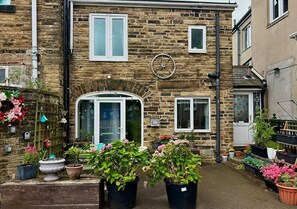 A stone building with a large arched entrance, potted plants, and a wheel on the wall. - Hidden Gem of Sheffield (Sheffield)