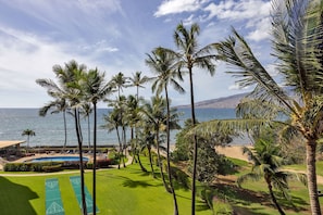 A resort with a pool, shuffleboard courts, palm trees, and a view of the ocean.