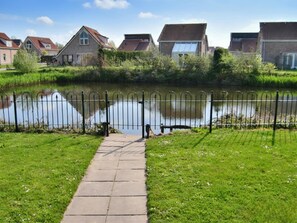 Un sentier qui mène à un plan d’eau paisible, bordé de maisons résidentielles.