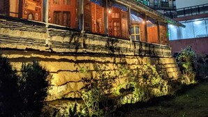 Un bâtiment à la façade en pierre et au toit plat, sous un ciel nocturne où l’on peut voir la lune.