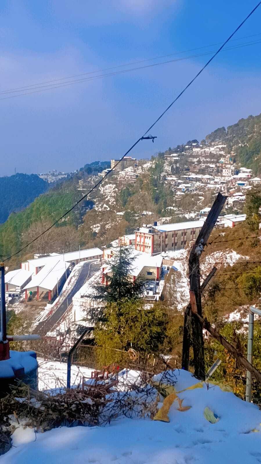 A mountainous landscape with buildings, a ski lift, and a snow-covered foreground.