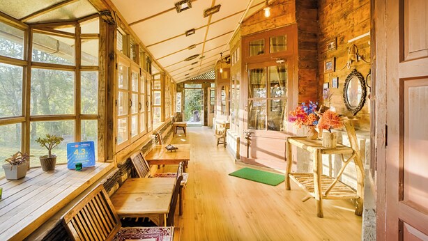 Un intérieur en bois, avec de grandes fenêtres, des meubles en bois et un mur en briques.