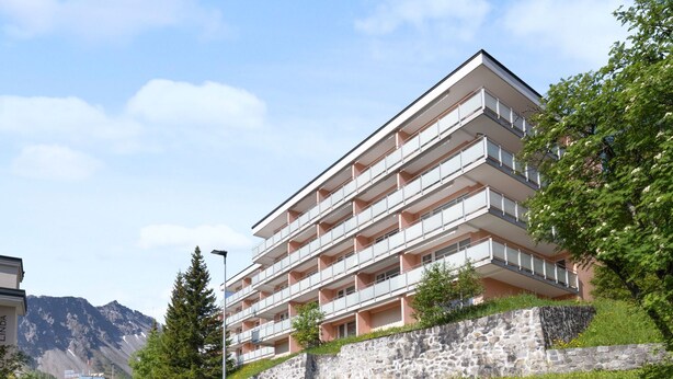 A multi-story hotel with balconies, situated on a hillside with a mountain backdrop. - Promenade Apt 016 by Interhome (Arosa)