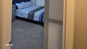 A bedroom with a bed, a nightstand, and a door with a number 2 sign.