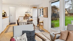A spacious living area with a dining table, sofas, and a large window offering a view of the outdoors.