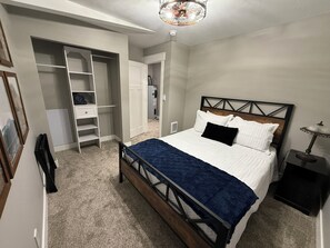 A bedroom with a bed, a wardrobe, a desk, and a ceiling light.