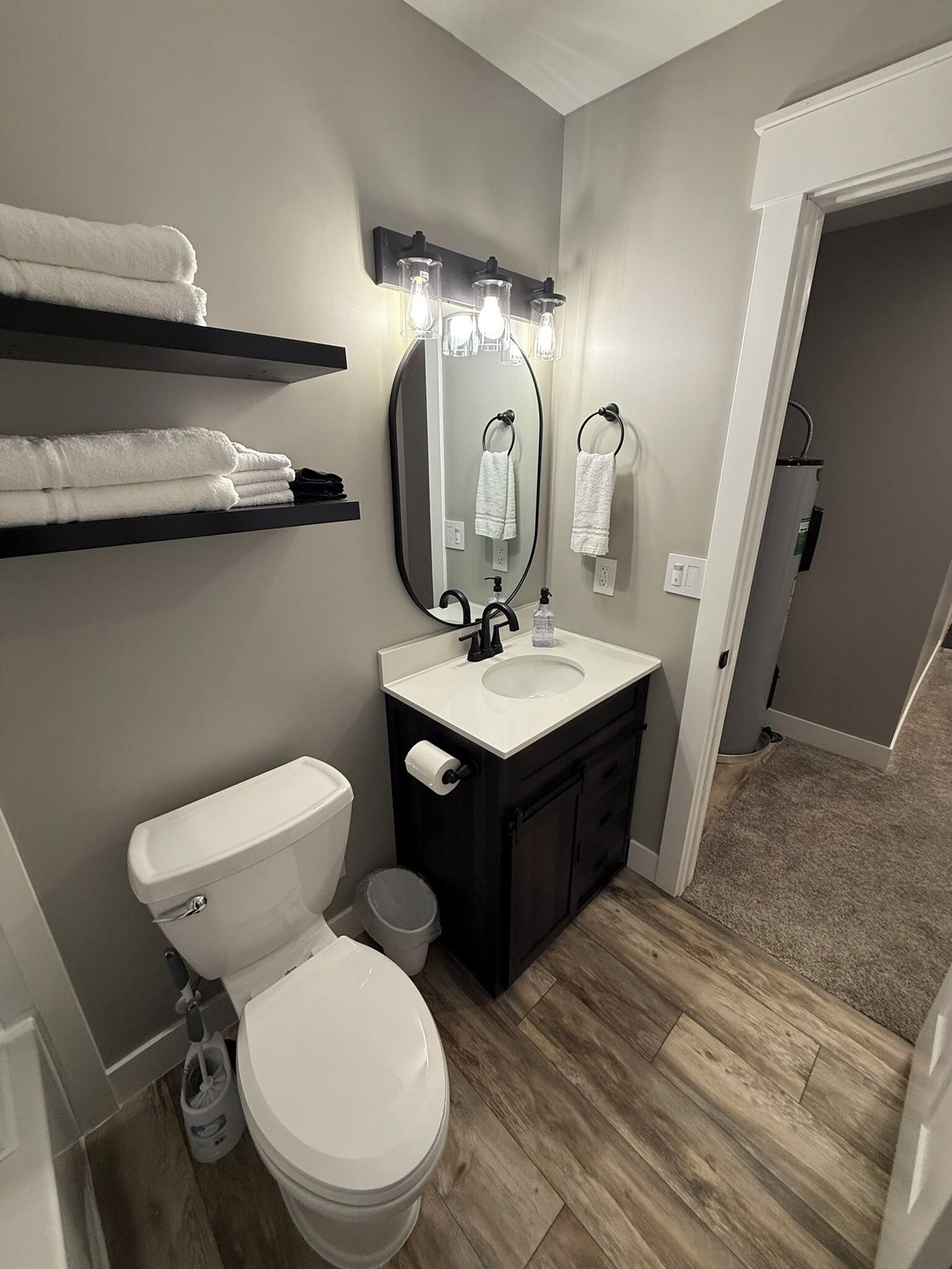 A modern bathroom with a toilet, sink, vanity, and towel racks.
