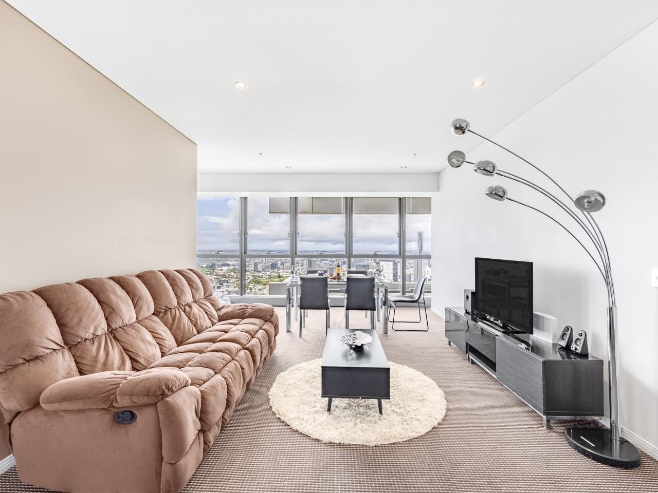 A modern living room with a large sofa, a coffee table, and a TV.