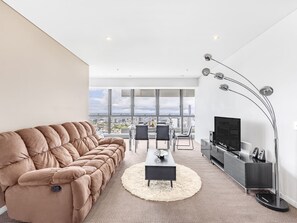 Una sala de estar moderna con un sofá grande, una mesa de centro y un televisor.