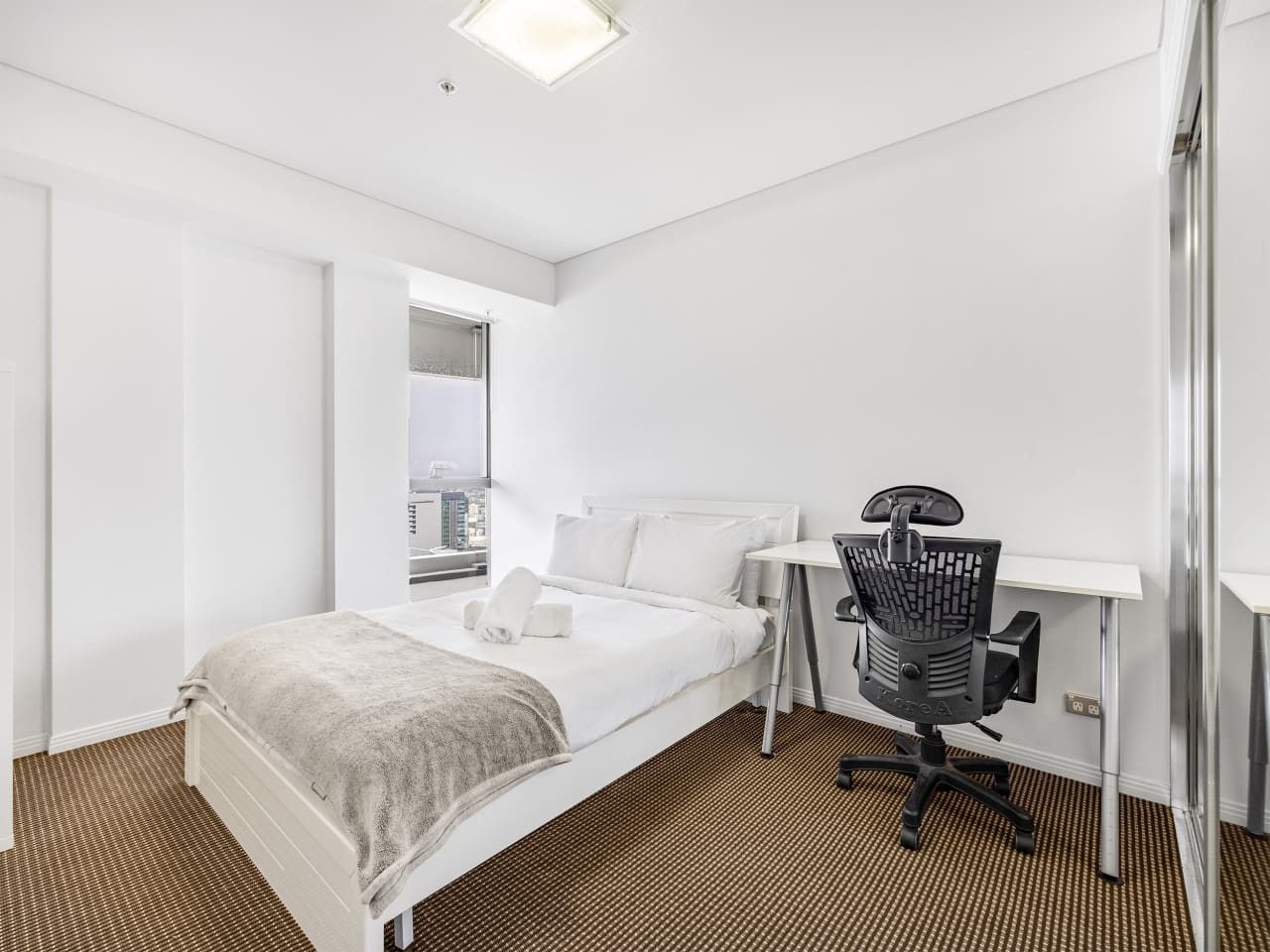 A hotel room with a bed, a desk, and a chair.