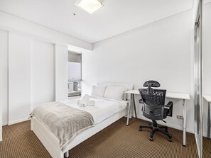 Una habitación de hotel con una cama, un escritorio y una silla.