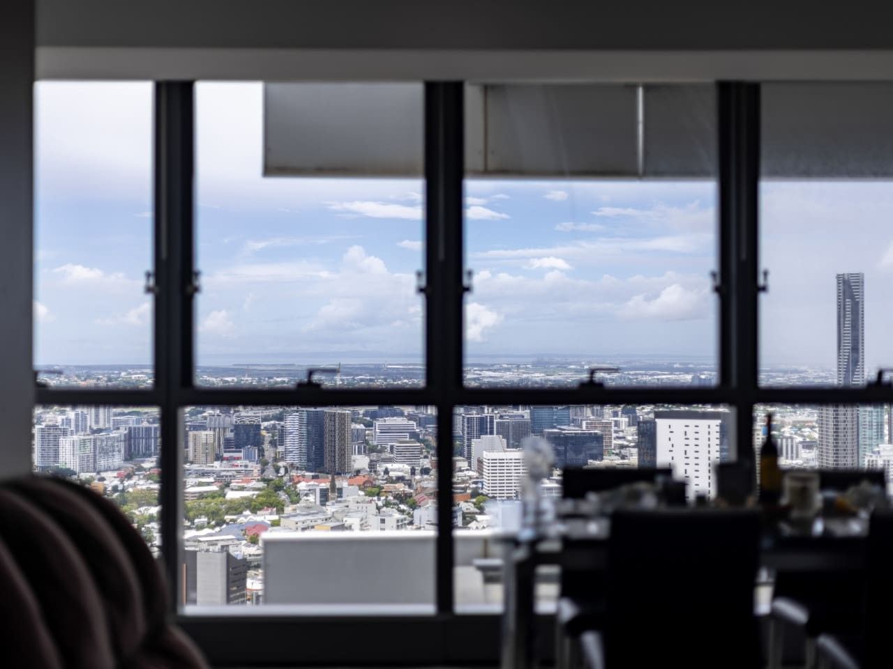 A view through a window with a cityscape, including buildings and a clear sky.