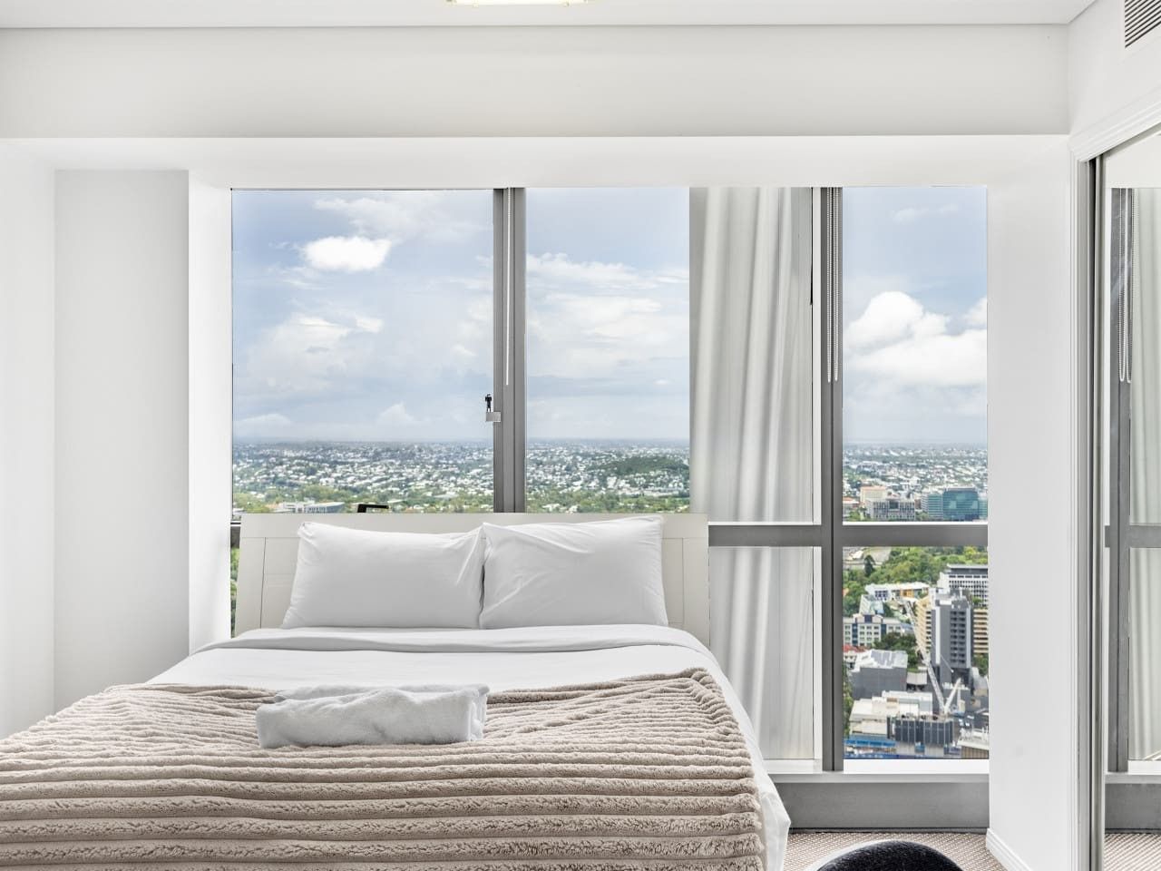 Une chambre d’hôtel avec un grand lit, une vue sur la ville et une fenêtre avec des rideaux.