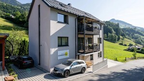 Ein zweistöckiges Gebäude mit Balkon, einem geparkten Auto davor und einem Schild, das es als Wohnhaus kennzeichnet.