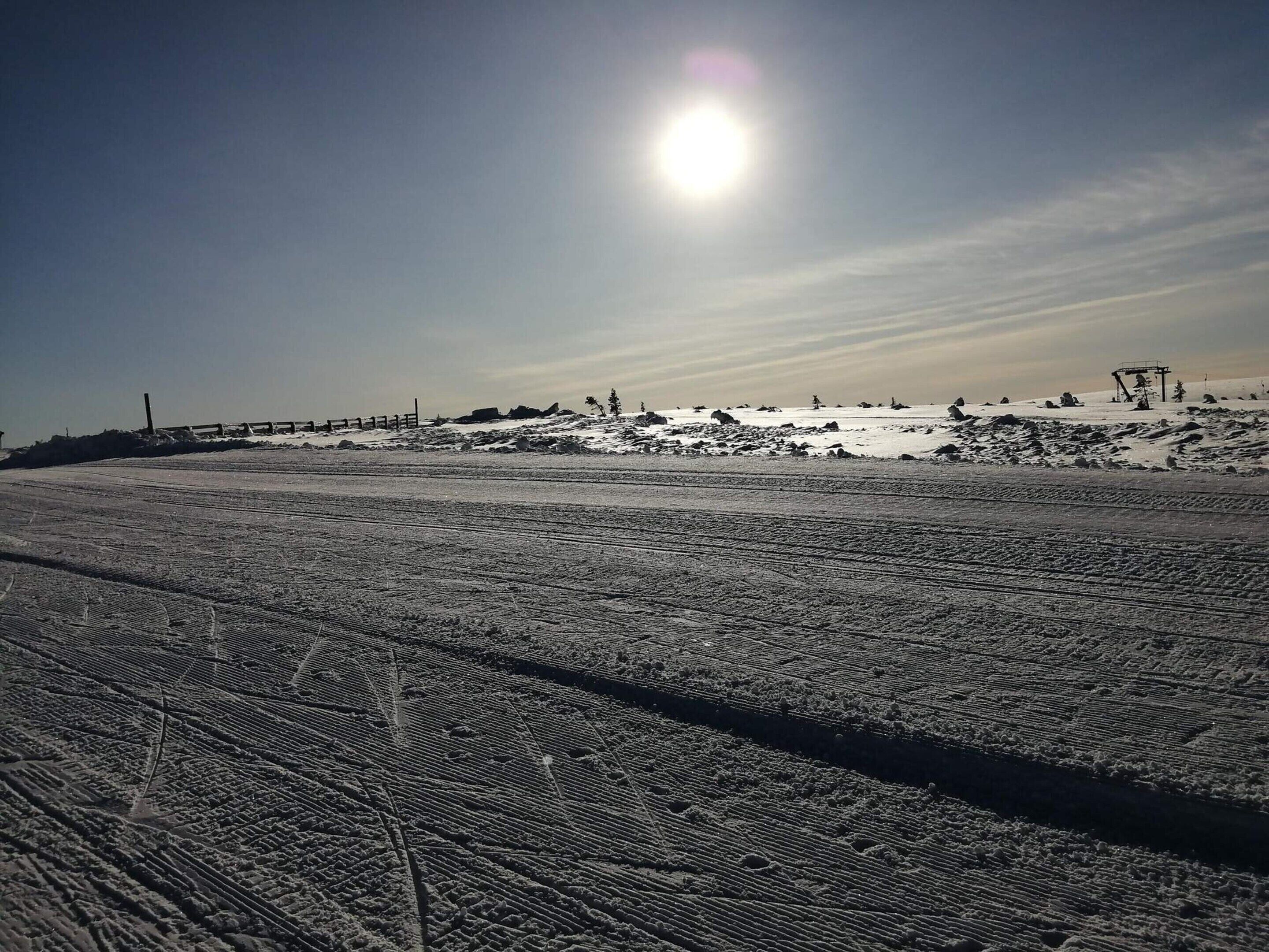 Un paisaje nevado con cielo despejado y el sol brillando.