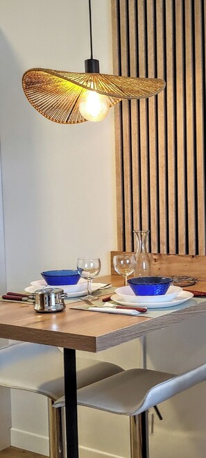 A dining table with blue bowls, wine glasses, and a pitcher, set against a wooden wall with vertical slats.