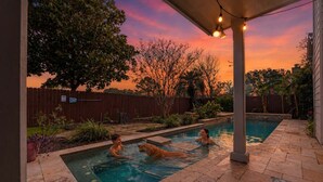Un jardin avec une piscine, une clôture en bois et un espace patio.