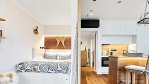Een moderne slaapkamer met een groot bed, een zacht wit vloerkleed en een houten vloer.