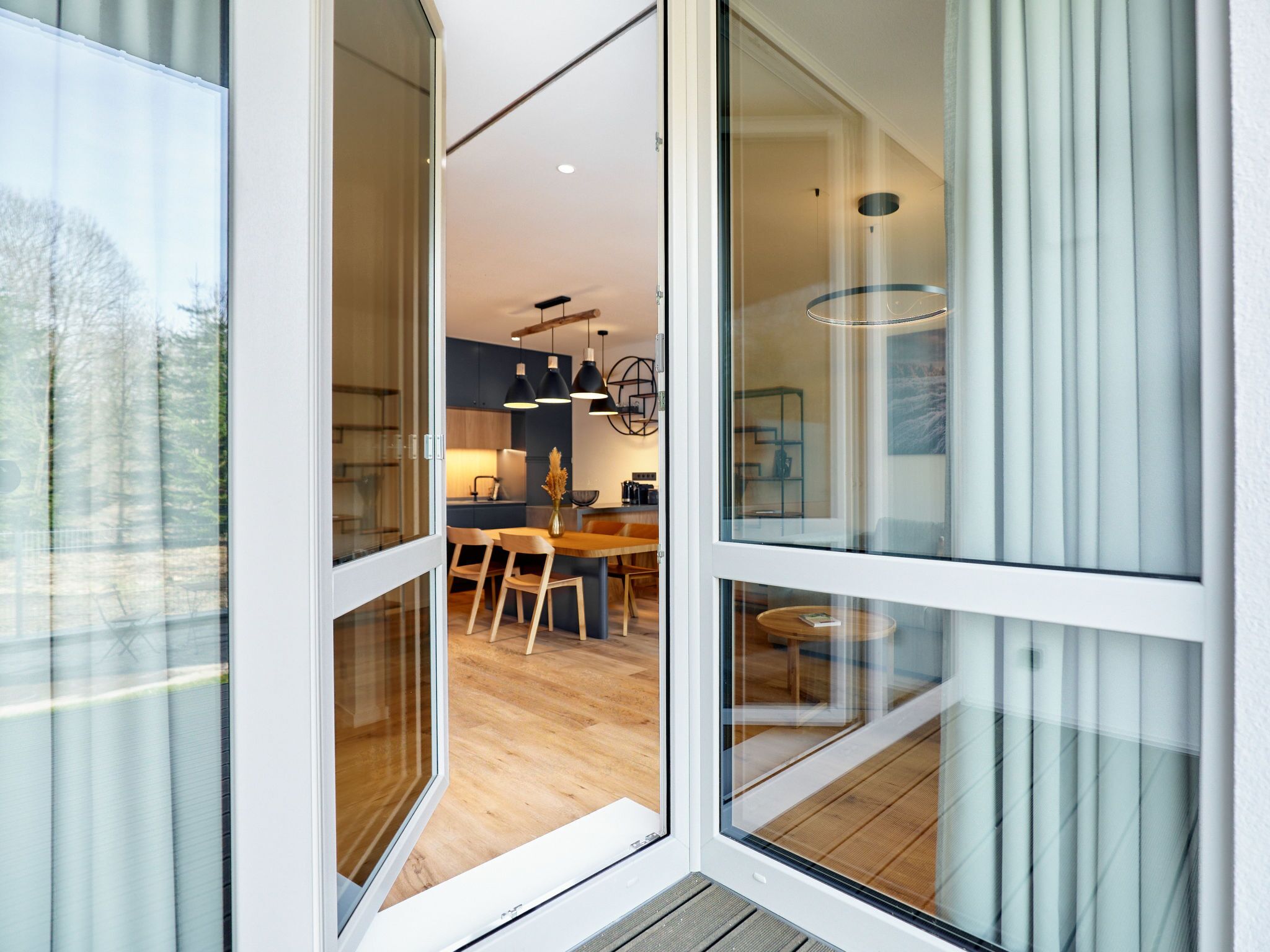 A modern interior with a dining area, kitchen, and large windows.
