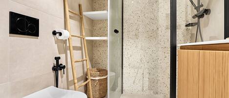 A modern bathroom with a toilet, a shower with a glass door, and a wooden vanity.