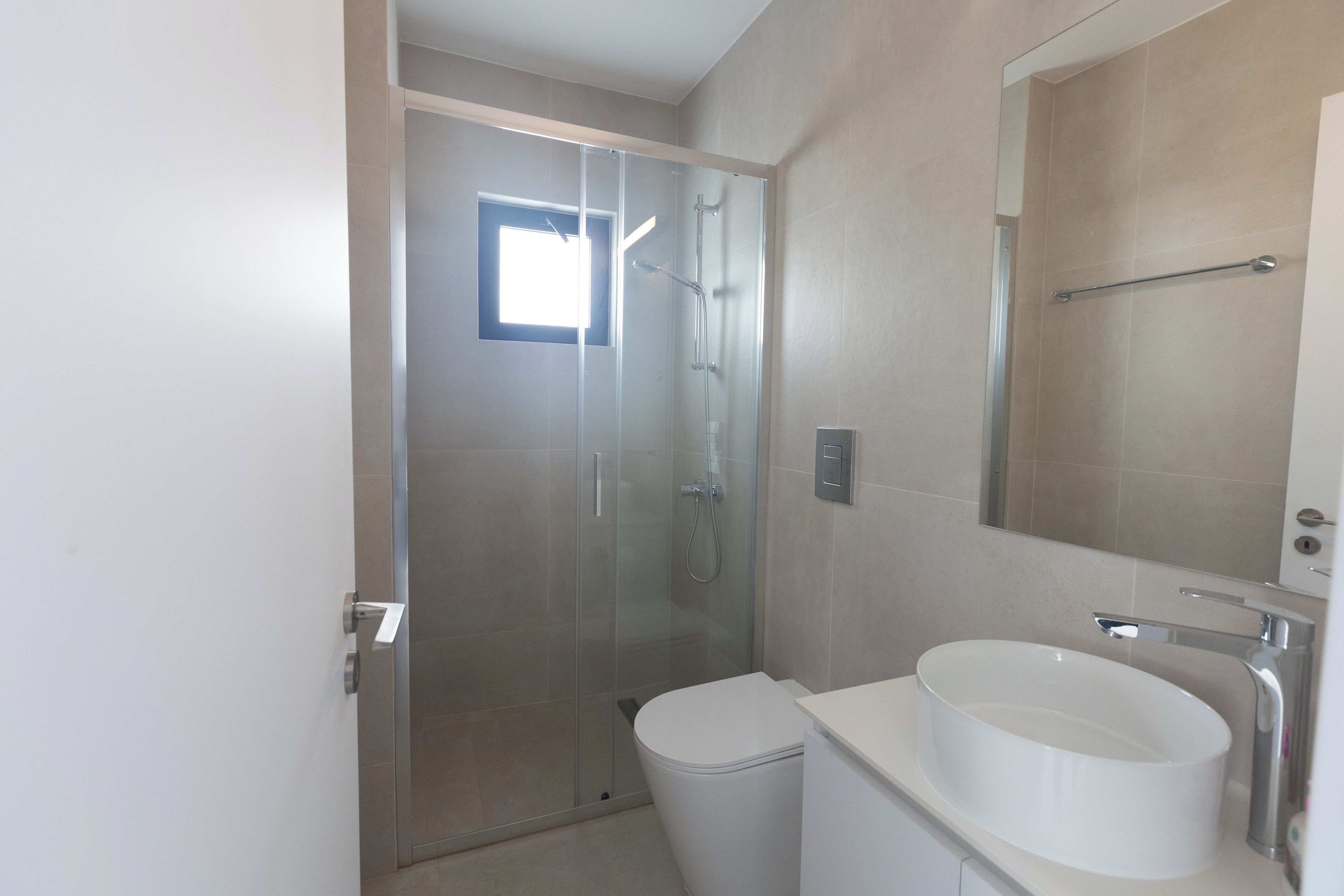 A modern bathroom with a glass-enclosed shower, a white sink, and a large mirror.