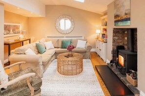 A cozy living room with a sofa, a round coffee table, a fireplace, and a wall-mounted mirror.