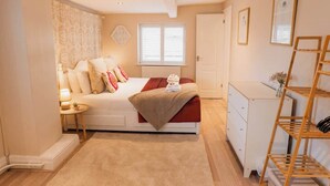 A bedroom with a bed, bedside table, lamp, and a wooden ladder. - Chester coach house with log burner & parking (Cheshire West and Chester)