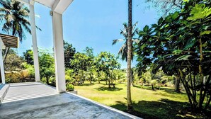 A covered outdoor area with a concrete floor, surrounded by lush greenery and palm trees. - Room in Guest Room - Serene Oasis in Galle - Tranquil Retreat With Breathtaking Views (Galle)