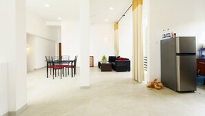 A modern kitchen with a stainless steel refrigerator, a dining area with a table and chairs, and a living area with a sofa and curtains. - Room in Guest Room - Serene Oasis in Galle - Tranquil Retreat With Breathtaking Views (Galle)