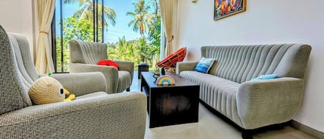 A modern living room with two grey sofas, a coffee table, and a large window with curtains.