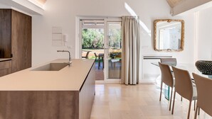 A modern kitchen with a large island, a dining area with chairs, and a view of the outdoors.